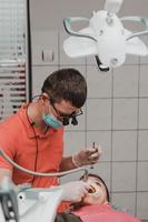 tratamiento dental de un niño, eliminación de caries con un taladro, boca abierta y eyector de saliva. foto