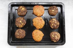 Chocolate cookies and strawberry has cashew nuts raisin in black tray on white wood table. photo