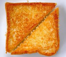 Two piece triangle slices of toasted bread made from white wheat flour and a slice of cheddar cheese in white plate. photo