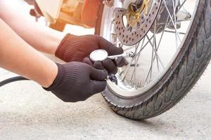 A man check inflator pressure of the tires with motorcycle with electric pump on road basic maintenance photo