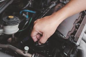 Hand a man open the Engine oil cap in engine room for check for Adding engine oil to engine car photo