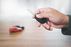 Close up hand of man holding and push remote control for lock and Unlock car , concept model toy a car in blur background photo