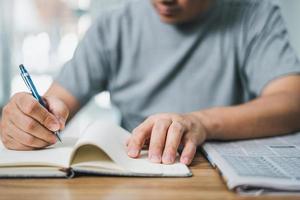 Man looking the newspaper for a new job and use pen write in notebook home while working at home photo