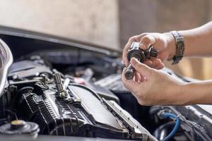 Close up hand Asia Technician check old spark plug coil in Maintenance service of gasoline  engine in garage photo