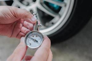 Car basic check , close up A man hold air pressure gauge and show display meter check tire air pressure in service concept photo