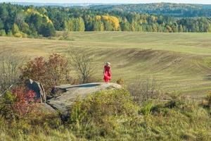 aerial view on girl in red dress on rock or concrete ruined structure photo