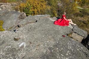 vista aérea de una chica vestida de rojo sobre roca o estructura en ruinas de hormigón foto