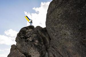 Welcome to Ukraine. Man hold ukrainian flag in big stone Pidkamin. photo