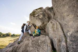 Father with son climbing big stone in hill. Pidkamin, Ukraine. photo