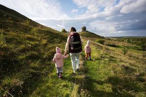 Kids exploring nature.  Mother with two daughters near big stone in hill. Pidkamin, Ukraine. photo