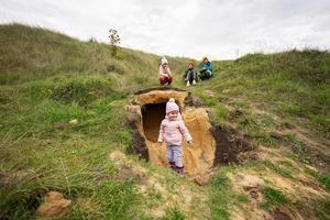 Four kids explore limestone stone cave at mountain. photo