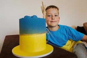 Ukrainian boy kid celebrating birthday holding big cake with flag of Ukraine. photo