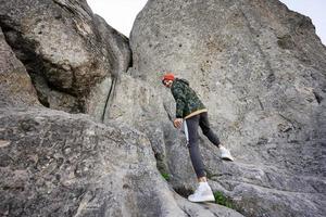 chico escalando una gran piedra en la colina. pidkamin, ucrania. foto