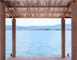 View on a blue sea from under an awning on a small concrete pier photo