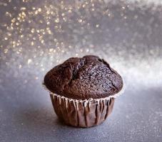 Tasty brown chocolate muffin on a silver sparkling background photo