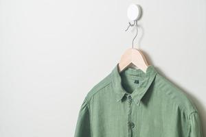 camisa colgante con colgador de madera en la pared foto