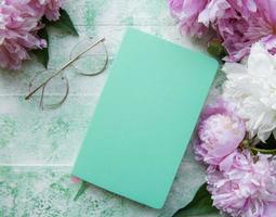 Flat lay paper notebook, eyeglasses, peony flowers photo