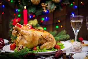 Baked turkey or chicken. The Christmas table is served with a turkey, decorated with bright tinsel and candles. Fried chicken, table. Christmas dinner. photo