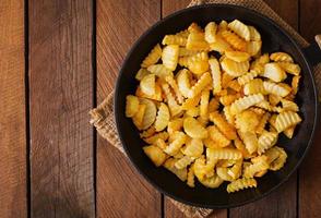 Frying pan with a fried potato in a rural way on a wooden background. photo