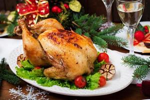 Baked turkey or chicken. The Christmas table is served with a turkey, decorated with bright tinsel and candles. Fried chicken, table. Christmas dinner. photo