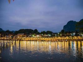 hermosa vista del río nam song con restaurante junto al río y la montaña en la noche en la ciudad de vangvieng lao. ciudad de vangvieng la famosa ciudad de destino de vacaciones en lao. foto