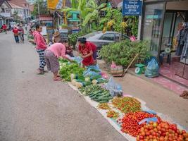 vangvieng.lao-5 de diciembre de 2017. gente local desconocida abre el puesto y vende verduras en la carretera en el centro de vangvieng por la mañana. ciudad de vangvieng, la famosa ciudad de destino de vacaciones en laos. foto