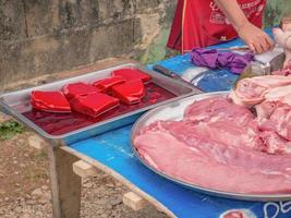 vangvieng.lao-5 dic 2017.personas locales desconocidas abren el puesto y venden carne de cerdo cruda en la carretera en el centro de vangvieng por la mañana. ciudad de vangvieng, la famosa ciudad de destino de vacaciones en laos. foto