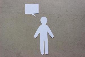 Silhouette of man cut out of white paper. With speech-bubble. In the center of photo on a beige background