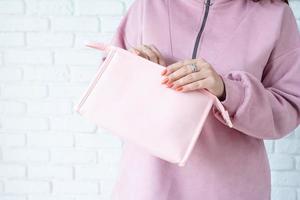 closeup woman in pink clothes hands holding pink toiletry bag for mockup photo