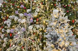 shop window decoration, shopping center decor. artificial white spruce with garlands. fir branches with round glass balls. and nearby trees with long light garlands photo