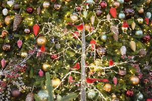 Christmas decor for a shopping center. tall fir trees in the center, decorated with bright garlands and glowing toys. glass toys on fir branches photo