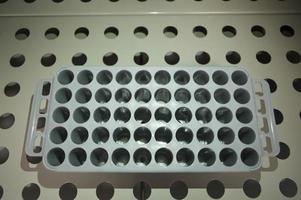 cropped shot of doctor holding test tubes in stand in front of tiled white wall photo