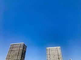 Two large high reinforced concrete, panel, monolithic-frame, frame-block houses, buildings, skyscrapers, new buildings with a glare of the sun in the windows against the blue sky photo