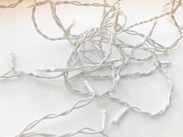 Twisted white wires of a garland in white rubber insulation with light bulbs on a white background photo