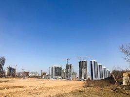 Building with the help of construction cranes of high reinforced concrete, panel, cast-frame, frame-block houses, buildings, skyscrapers, new buildings on the background of sandy land photo