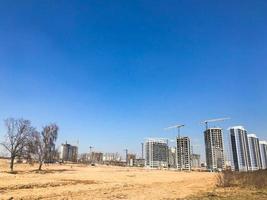 Building with the help of construction cranes of high reinforced concrete, panel, cast-frame, frame-block houses, buildings, skyscrapers, new buildings on the background of sandy land photo