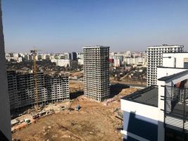Building with the help of construction cranes of high reinforced concrete, panel, cast-frame, frame-block houses, buildings, skyscrapers, new buildings on the background of sandy land photo