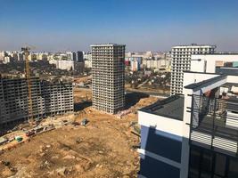Building with the help of construction cranes of high reinforced concrete, panel, cast-frame, frame-block houses, buildings, skyscrapers, new buildings on the background of sandy land photo