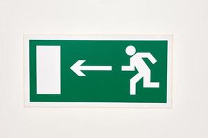 The sign of the direction to the evacuation exit on the wall in the shopping center photo