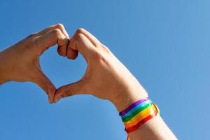 mano haciendo un signo de corazón con la pulsera de la bandera del arco iris lgbt del orgullo gay foto