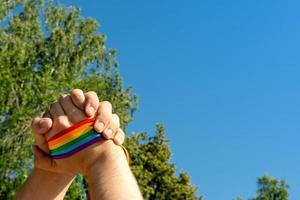 Hand making sign of friendship and equality with gay pride LGBT rainbow flag wristband photo