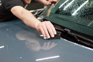 instalación de una película protectora de pintura y barniz transparente en el coche. Película de poliuretano ppf para proteger la pintura del coche de piedras y arañazos. foto