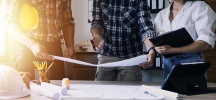 Construction engineer working at blueprint to build large commercial buildings in office. Engineering tools and construction concept. photo