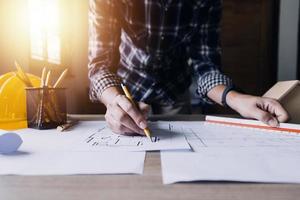Construction engineer working at blueprint to build large commercial buildings in office. Engineering tools and construction concept. photo