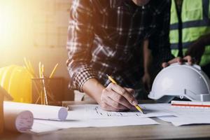 Construction engineer working at blueprint to build large commercial buildings in office. Engineering tools and construction concept. photo
