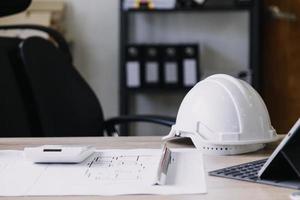 ingeniero de construcción que trabaja en planos para construir grandes edificios comerciales en la oficina. herramientas de ingeniería y concepto de construcción. foto