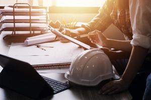 Construction engineer working at blueprint to build large commercial buildings in office. Engineering tools and construction concept. photo