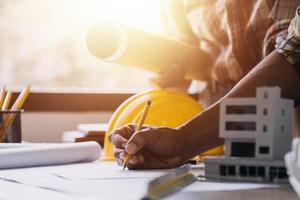 Construction engineer working at blueprint to build large commercial buildings in office. Engineering tools and construction concept. photo