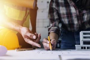 Construction engineer working at blueprint to build large commercial buildings in office. Engineering tools and construction concept. photo