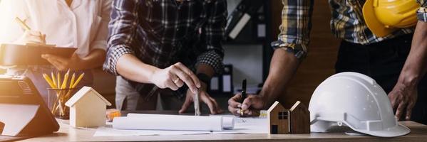 Construction engineer working at blueprint to build large commercial buildings in office. Engineering tools and construction concept. photo